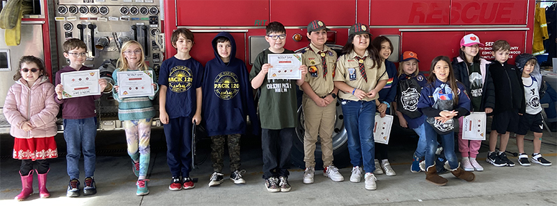 Kids holding Scout Day certificates lined up next to a fire engine