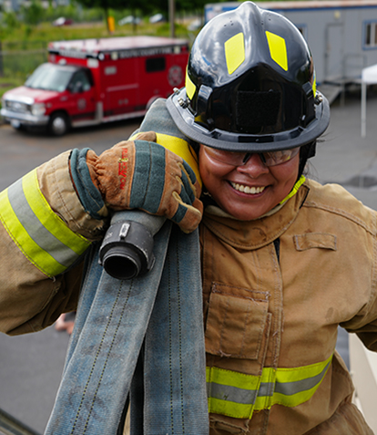 Female firefighter carrying hose on her shoulder